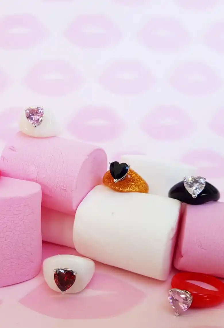 Assorted heart-shaped gemstone rings displayed on marshmallows.