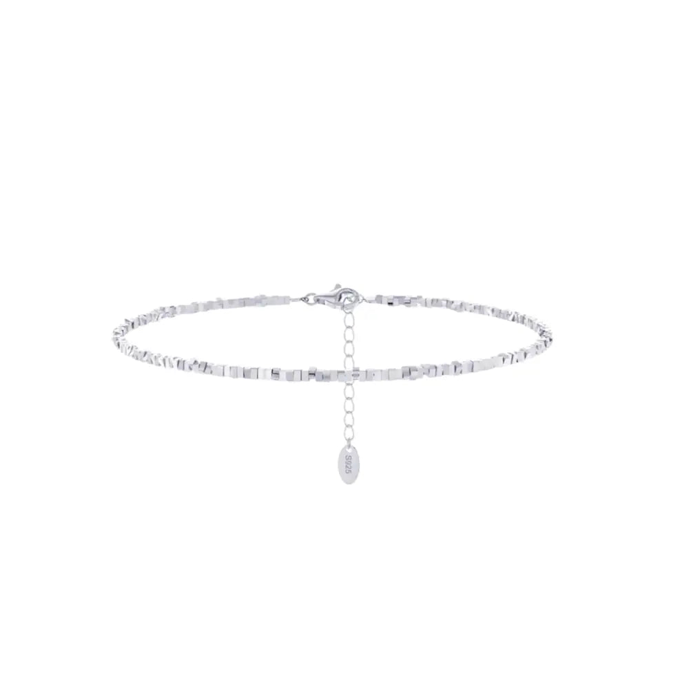 A silver-colored anklet with square-cut links and a small dangling charm, displayed against a white background.