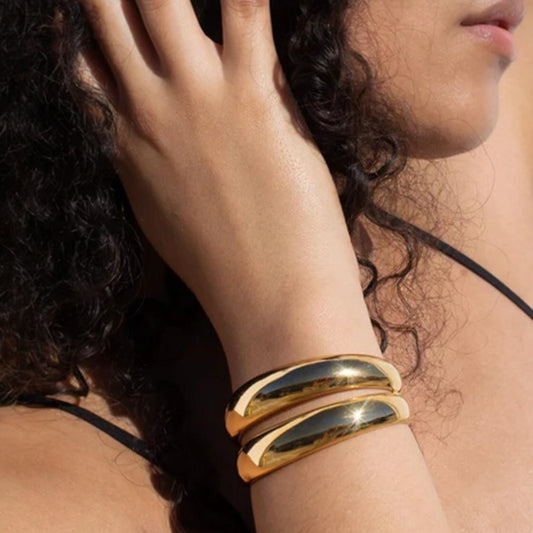 Scandal Kiss gold double band bangle in polished 18ct gold plated stainless steel worn on a model's wrist