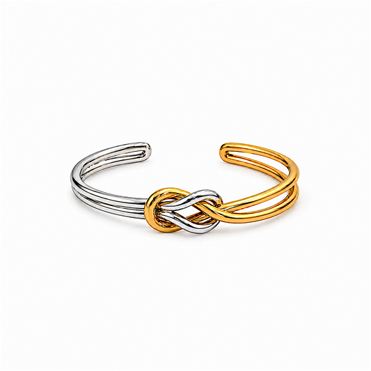 Scandal Kiss two-tone open cuff bracelet featuring a polished gold and silver intertwined knot design.